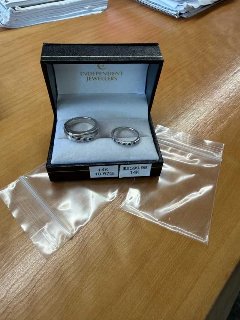 Two diamond rings displayed in an open jewellery box beside two small baggies